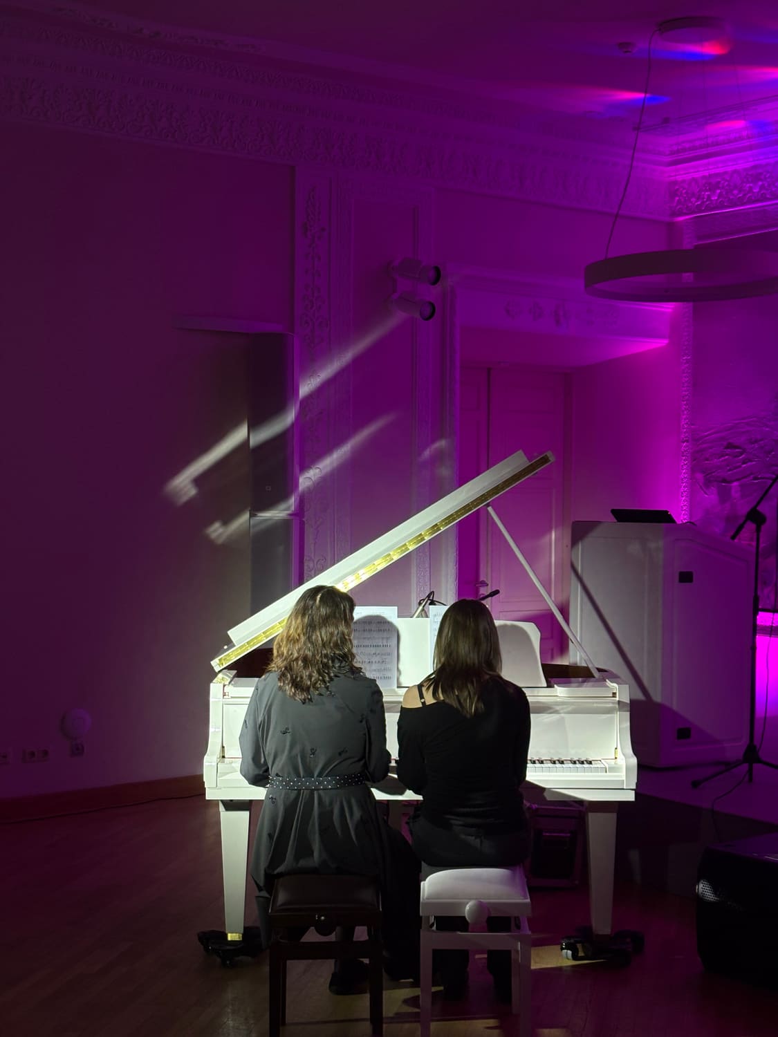Baltas fortepijonas violetiniame scenos apšvietime